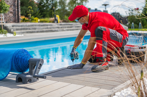 Mann im roten Arbeitsgewand installiert einen rutschfesten Boden im Poolbereich zur Verbesserung der Sicherheit.